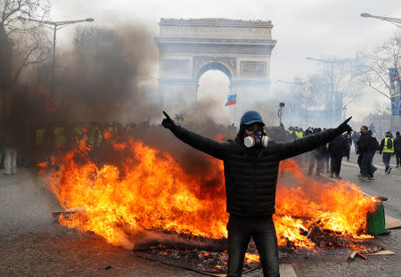 A protester stands in front of burning barricade during a demonstration by the "yellow vests" movement in Paris, France, March 16, 2019. REUTERS/Philippe Wojazer