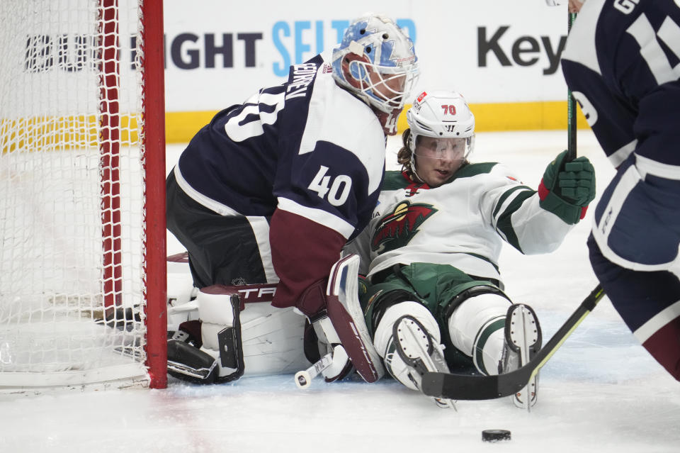 Minnesota Wild center Oskar Sundqvist, right, slides into Colorado Avalanche goaltender Alexandar Georgiev while pursuing the puck in the second period of an NHL hockey game Wednesday, March 29, 2023, in Denver. (AP Photo/David Zalubowski)