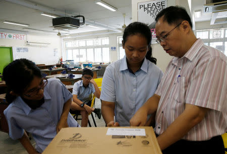 A student looks on as a teacher demonstrates spray painting during a model aeroplane assembly enrichment class at a secondary school in Singapore October 27, 2016. Picture taken October 27, 2016. REUTERS/Edgar Su