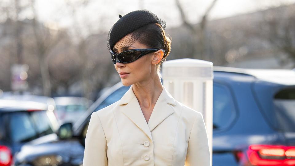 Sabina Jakubowicz wears beige tailored jacket, tights, black shorts, hat, sunglasses, bag, heels outside Dior during the Haute Couture Spring/Summer 2024 