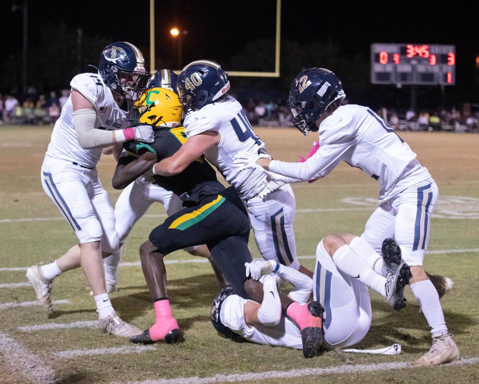 Ja'bril Rawls (6) is taken down by a pod of Dolphins during the Gulf Breeze vs Catholic football game at Pensacola Catholic High School in Pensacola on Thursday, Oct. 6, 2022.