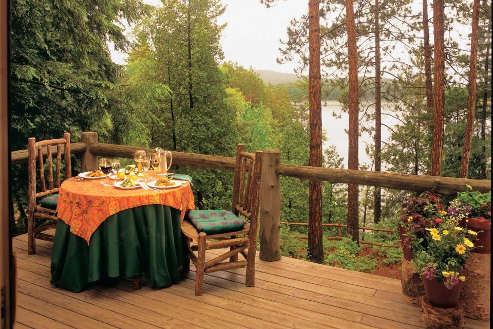 A table set for dinner on the terrace of The Point Hotel, set among tall green trees and with views to the water