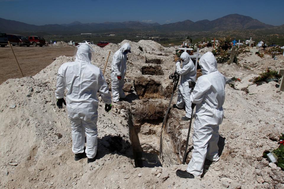 Cemetery workers wearing protective suits lower the coffin of a coronavirus victim in a pit at the municipal cemetery, amid the spread of the coronavirus disease, in Tijuana, Mexico on April 22.