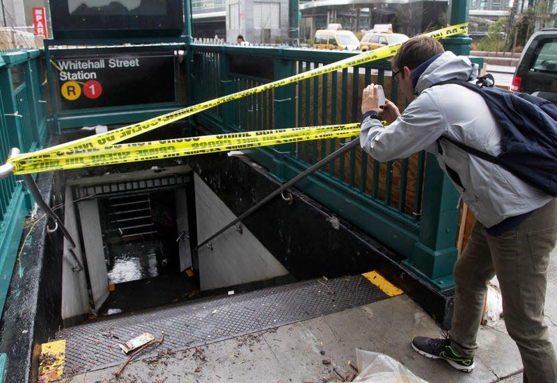 A man uses his mobile phone to photograph a closed and flooded subway station in lower Manhattan, in New York, Tuesday, Oct. 30, 2012.