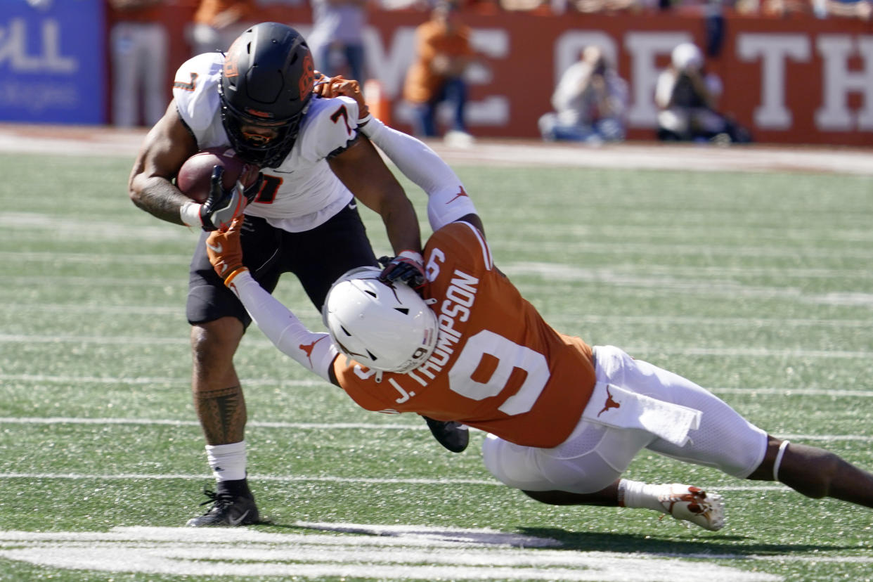 Oklahoma State running back Jaylen Warren (7) is tackled by Texas defensive back Josh Thompson (9) during the first half of an NCAA college football game in Austin, Texas, Saturday, Oct. 16, 2021. (AP Photo/Chuck Burton)