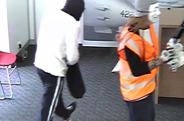 The pair appear to be carrying a sawn-off shotgun as they entered the Bendigo Bank at Laverton. Source: Victoria Police