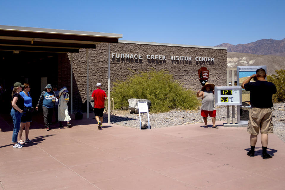 Tourists take photographs with the thermometer at the Furnace Creek Visitor Center during a dangerous heat wave, Tuesday, July 9, 2024, in Death Valley, Calif. The thermostat is imprecise, registering the temperature anywhere from 1 to 5 degrees Fahrenheit higher than more precise instruments and providing a more impressive reading for pictures. (AP Photo/Ty ONeil)