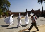 Penitents walk on their way to a church before taking part in the procession of "La Paz" (The Peace) brotherhood on Palm Sunday in the Andalusian capital of Seville, southern Spain, April 13, 2014. Holy Week is celebrated in many Christian traditions during the week before Easter. REUTERS/Marcelo del Pozo (SPAIN - Tags: RELIGION SOCIETY)