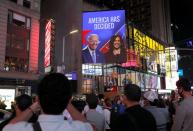 People celebrate as media announced that Democratic U.S. presidential nominee Joe Biden and vice presidential nominee Kamala Harris (seen on screen) have won the 2020 U.S. presidential election on Times Square in New York City