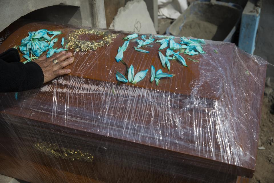 A relative of Joaquin Alonso touches the coffin of the 58-year-old who died of COVID-19 during his burial at the cemetery "Martires 19 de Julio" in Comas on the outskirts of Lima, Peru, Tuesday, July 28, 2020. Peruvian authorities and the Pan American Health Organization are investigating whether the country failed to classify just over 27,000 deaths as caused by the novel coronavirus, a figure that could more than double the country's official death toll from the disease. (AP Photo/Rodrigo Abd)