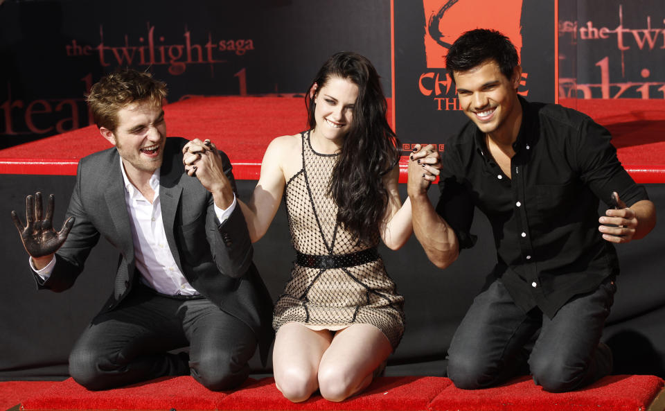 Actors Robert Pattinson (L), Kristen Stewart and Taylor Lautner hold hands after putting their handprints in cement during a hand and footprint ceremony at the Grauman's Chinese Theatre in Hollywood, California November 3, 2011.    REUTERS/Mario Anzuoni (UNITED STATES - Tags: ENTERTAINMENT)