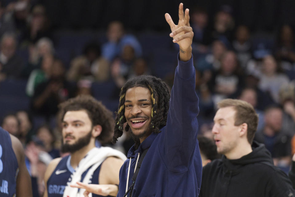 Memphis Grizzlies guard Ja Morant, center, cheers for his team in the first half of an NBA basketball game against the Sacramento Kings, Monday, Jan. 29, 2024, in Memphis, Tenn. (AP Photo/Nikki Boertman)