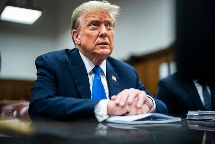 Former President Donald Trump seated in a hearing, wearing a dark suit and tie