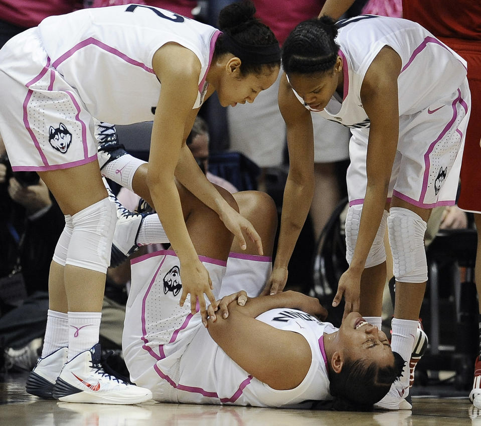 Connecticut's Kaleena Mosqueda-Lewis holds her arm after a hard fall to the court as teammates Saniya Chong, left, and Moriah Jefferson, right, look over her during the first half of an NCAA college basketball game on Sunday, Feb. 9, 2014, in Storrs, Conn. (AP Photo/Jessica Hill)