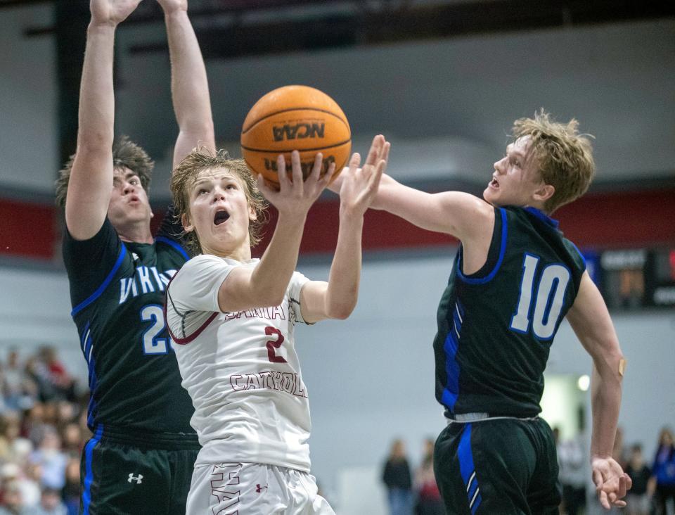 Santa Fe Catholic junior Tate Darner goes up for a layup between Lakeland Christian's Nate Carpenter (23) and Matthew Stephens (10) on Friday night.