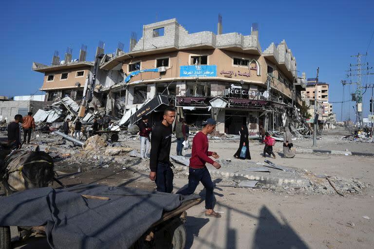 Palestinos pasan junto a edificios destruidos por un bombardeo israelí, en el campo de refugiados de Nusseirat, en la Franja de Gaza