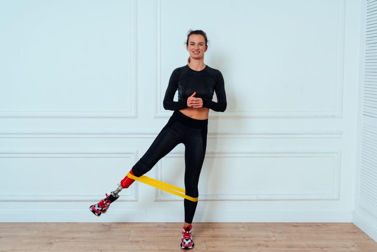 full length portrait of woman exercising against wall