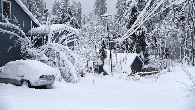 Rumah dan kendaraan yang diselimuti salju di Nevada City, California (27/12/2021). Banyak warga yang tidak mendapatkan listrik atau terjebak di salju. (Elias Funez/The Union via AP)