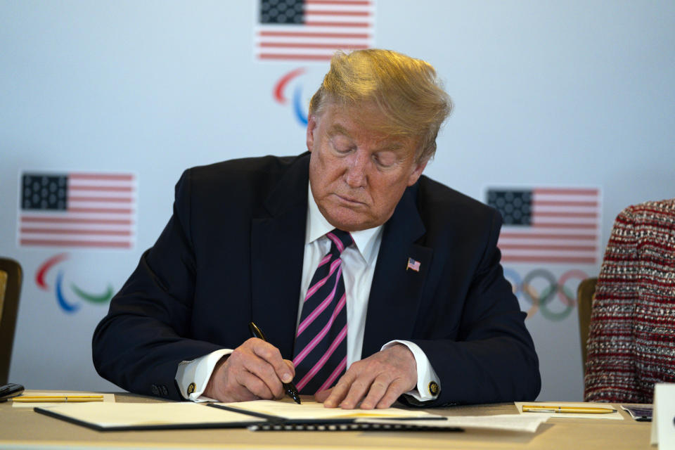 President Donald Trump signs a document pledging the support of the federal government during a briefing with the U.S. Olympic and Paralympic Committee and Los Angeles 2028 organizers, Tuesday, Feb. 18, 2020, in Beverly Hills, Calif. (AP Photo/Evan Vucci)