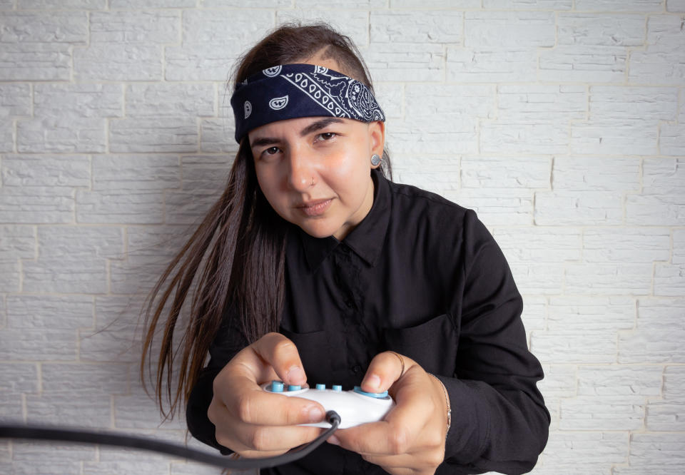 Alternative woman with cool hairstyle competing in video games holding gamepad. Leisure, enjoyment, gamer, competition concept.