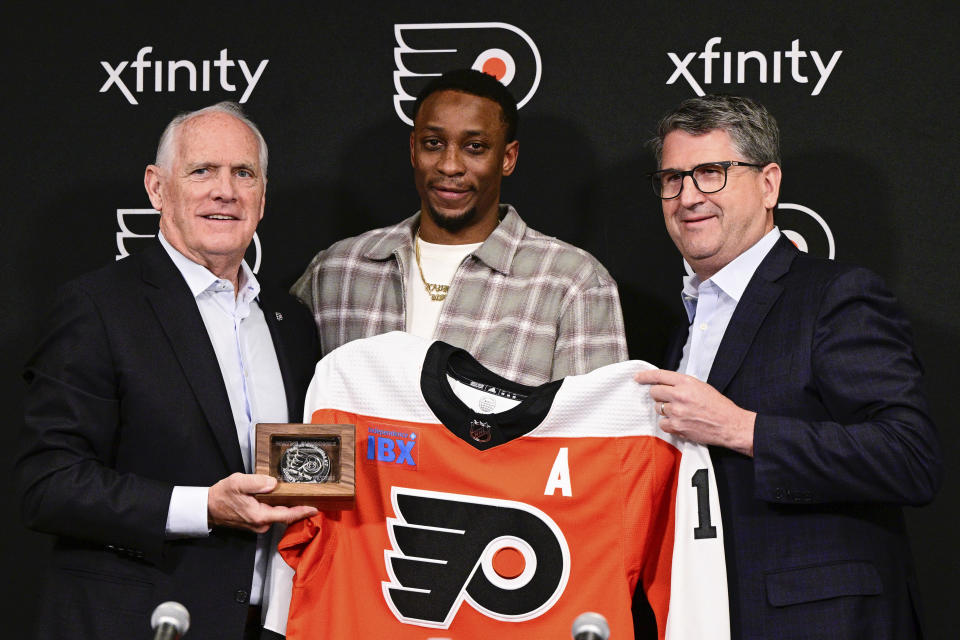 Former Philadelphia Flyers' Wayne Simmonds, center, poses for a photo with Flyers Governor and CEO of Comcast Spectacor Dan Hilferty, left, and President of Hockey Operations Keith Jones, right, after a press conference prior to an NHL hockey game, Saturday, April 13, 2024, in Philadelphia. Simmonds signed a one-day contract retiring a Philadelphia Flyer. (AP Photo/Derik Hamilton)