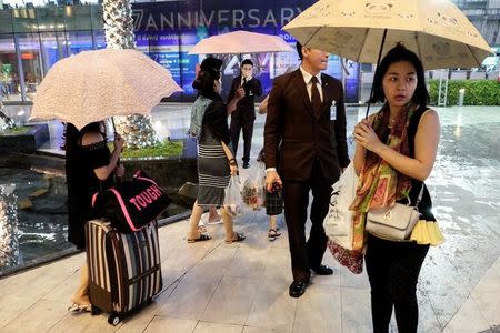 Tourists hold up umbrellas at a department store in Bangkok, Thailand, September 21, 2016. REUTERS/Athit Perawongmetha