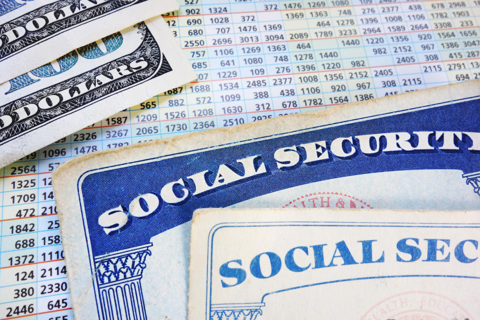 Two Social Security cards, and two hundred dollar bills, lying atop a Social Security payout card.