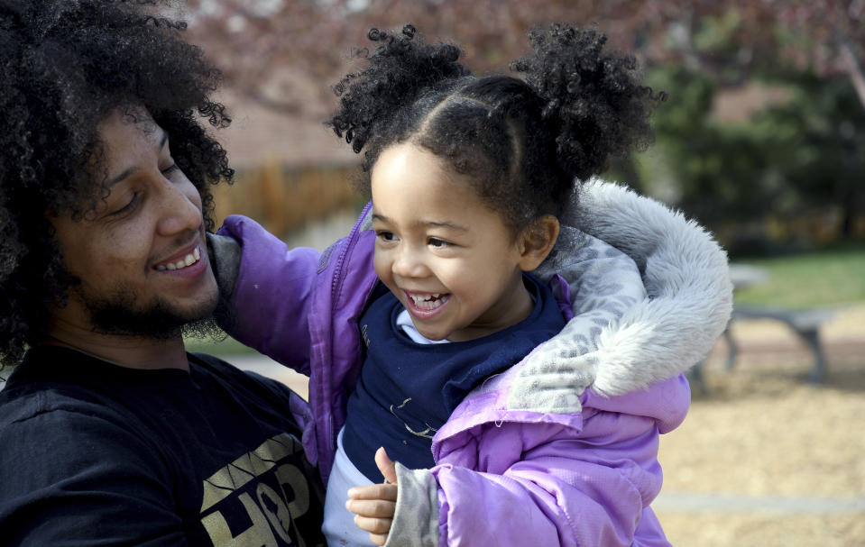 Michael Diaz-Rivera plays with his 2-year-old daughter Aria at a Denver park on Friday, April 23, 2021. Diaz-Rivera was pulled over in Colorado Springs, Colorado in 2006, and officers found two bags of marijuana in his car. After he was convicted of felony drug possession, he struggled to find housing, ran into hurdles while applying for federal student aid and was denied jobs. Now an elementary school teacher, he sees his future in a pot delivery business made possible by Colorado's marijuana social equity program, which is aimed at correcting past wrongs from the war on drugs. Diaz-Rivera says he hopes his business will allow him to pass on to his children generational wealth that he did not have growing up. (AP Photo/Thomas Peipert)