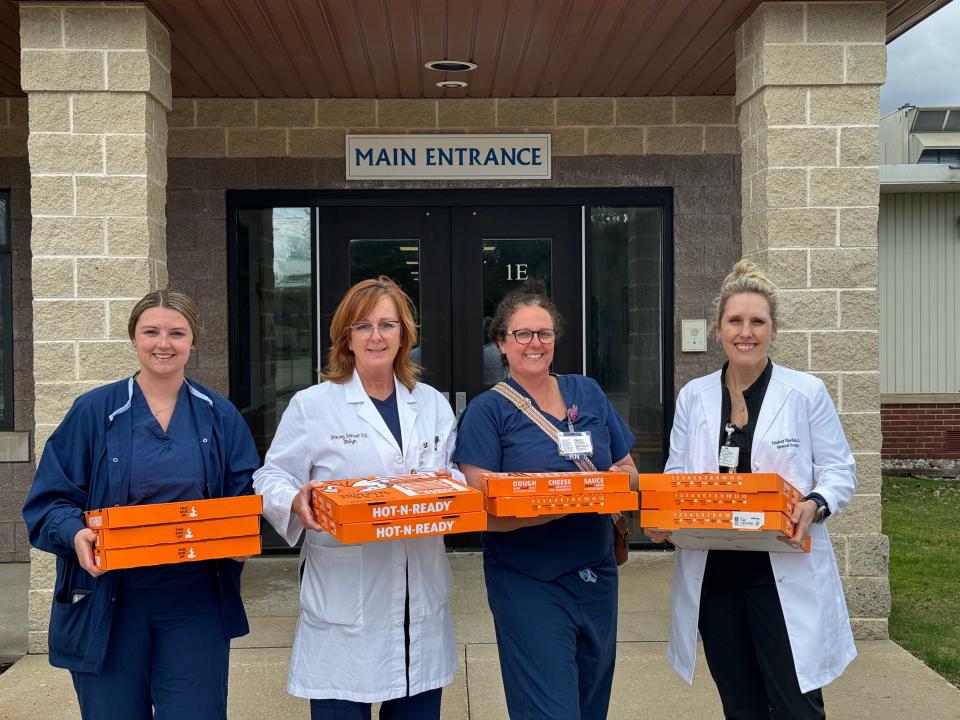 (From left) RaeAnne Rohn, a certified surgical technologist, Dr. Stacey Sensor, Nisa Curtis, a nurse and robotic care specialist, and Dr. Lindsay Harden carry pizzas into St. Mary Cathedral School in Gaylord on May 1 to reward students for coming up with the name "Wally" for the surgical robot at Munson Otsego Memorial Hospital.