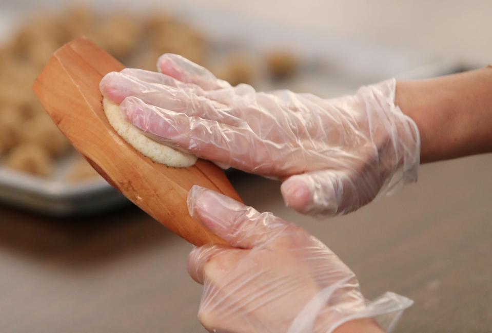 A member of Our Lady of the Cedars prepares a ma'mool cookie with dates using a wood mold called a kaleb.