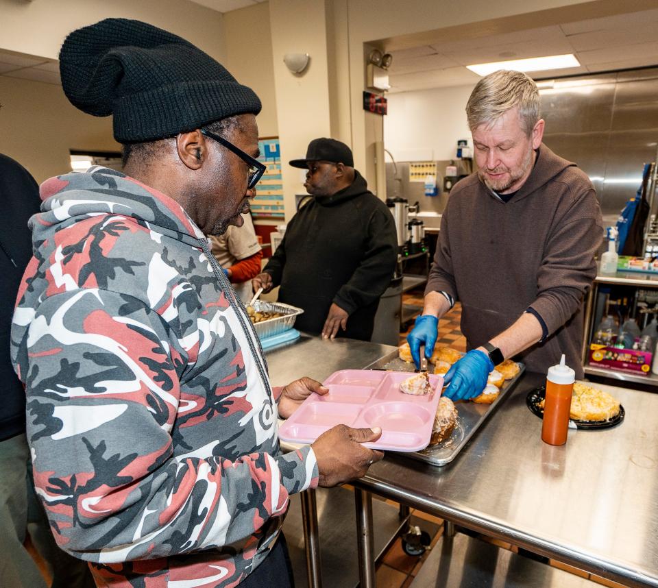 Maurice Spann receives a light meal from Brother Henryk Cisowski at the St. Ben's Community Meal hall, where volunteers and staff serve dinner then set out cots for an overnight warming center. Guests are served additional food later in the evening.