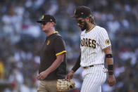 San Diego Padres shortstop Fernando Tatis Jr., right, walks off the field with a trainer in the fifth inning of a baseball game against the Cincinnati Reds, Saturday, June 19, 2021, in San Diego. (AP Photo/Derrick Tuskan)