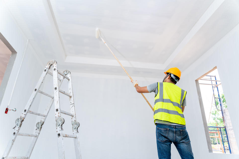 A worker painting a ceiling
