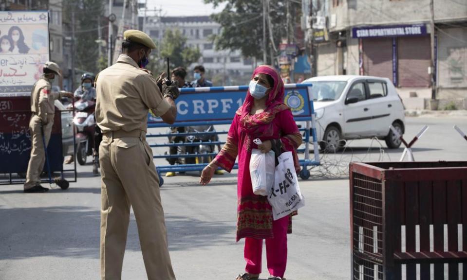 A Kashmiri woman asks a police officer if she can cross the street in Srinagar.