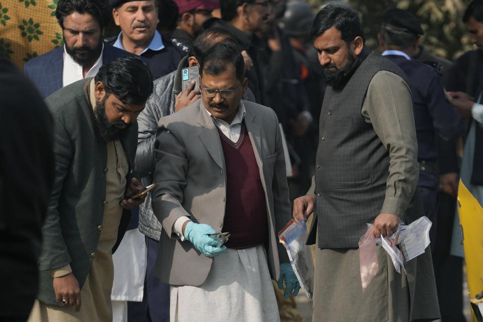 Investigators collect evidence from the wreckage of a car at the site of bomb explosion, in Islamabad, Pakistan, Friday, Dec. 23, 2022. A powerful car bomb detonated near a residential area in the capital Islamabad on Friday, killing some people, police said, raising fears that militants have a presence in one of the country's safest cities. (AP Photo/Anjum Naveed)