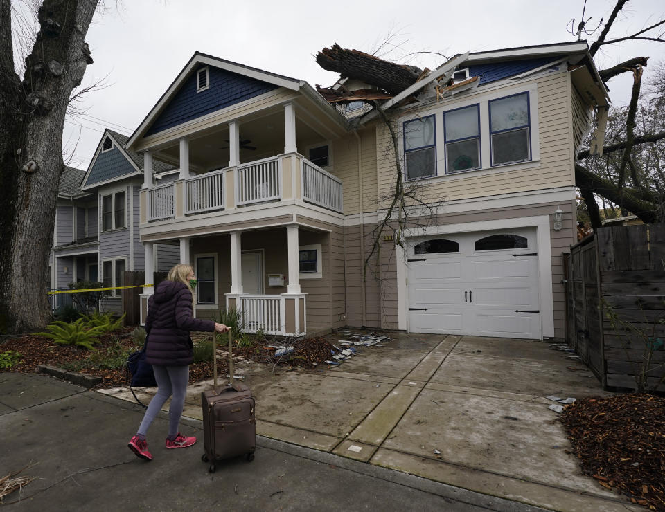 Amy Lilly returns to her home to get some belongings after she was forced to leave during the night when a storm caused a tree limb to crash into her house in Sacramento, Calif., Wednesday, Jan. 27 2021. High-winds and rain pelted the region causing damage throughout the area. (AP Photo/Rich Pedroncelli)