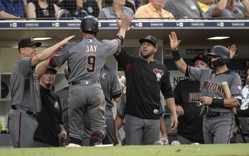 Arizona Diamondbacks' Jon Jay (9) is welcomed in the dugout after scoring on a sacrifice fly by A.J. Pollock during the fifth inning of a baseball game against the San Diego Padres in San Diego, Saturday, Aug. 18, 2018. (AP Photo/Kyusung Gong)