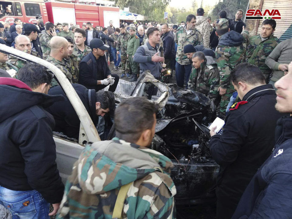 In this photo released by the Syrian official news agency SANA, Syrian security forces inspect a burned car at the site of an explosion, in the coastal city of Latakia, Syria, Tuesday, Jan. 22, 2019. Syrian state TV said Tuesday's blast was a car bomb that went off in Al-Hammam Square in Latakia that has been a government stronghold since the conflict began in March 2011. (SANA via AP)