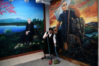 A woman sweeps near murals depicting Oscar Romero, at the Divina Providencia parish in San Salvador, on October 11, 2018