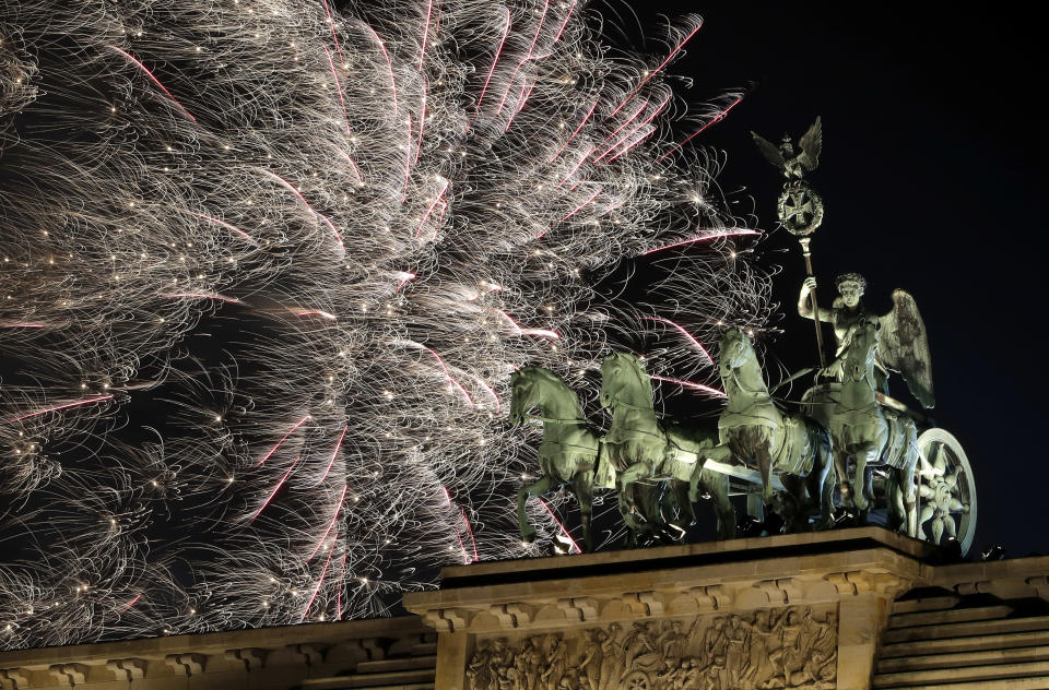 Fireworks light the sky above the Quadriga at the Brandenburg Gate shortly after midnight in Berlin, Germany, Tuesday, Jan. 1, 2019. Hundred thousands of people celebrated New Year's Eve welcoming the new year 2019 in Germany's capital. (AP Photo/Michael Sohn)