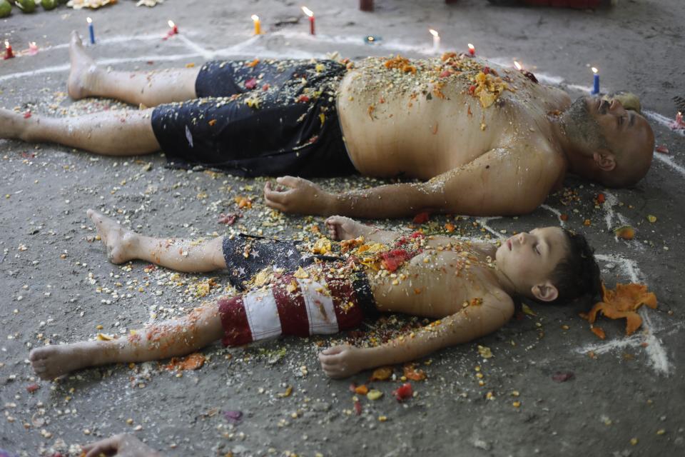 In this photo taken Oct. 13, 2019, a man and boy lie with their eyes closed amid candles inside a circle, called an oracle, made of white powder during a ritual for prosperity on Sorte Mountain where followers of indigenous goddess Maria Lionza gather annually in Venezuela's Yaracuy state. Venezuela is predominantly Roman Catholic, whose church disapproves of the folk religion but has long since abandoned its attempts to suppress it. (AP Photo/Ariana Cubillos)