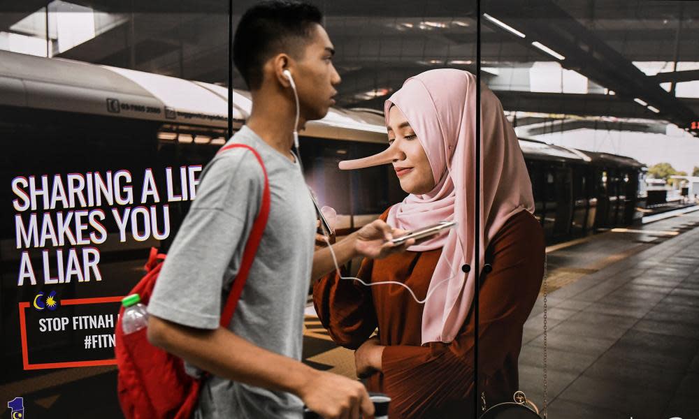 A commuter walks past an advertisement ti discourage ‘fake news’ in Kuala Lumpur, Malaysia.