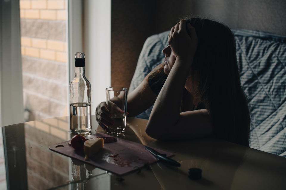 A woman who appears to be sad sitting at a table with a glass of water