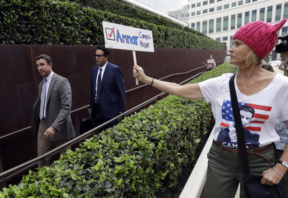 Rep. Duncan Hunter, left, leaves court as a woman holds a sign for his opponent, Ammar Campa-Najjar, on Sept. 24, 2018, in San Diego. (Photo: Gregory Bull/AP)