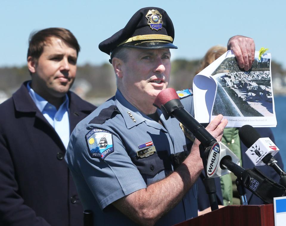 Rye Police Chief Kevin Walsh holds a photo of one of the boulders pushed onto the sidewalk from one of the storms this winter. He asked for people to be patient during the rebuilding process. In the background is U.S. Representative Chris Pappas.