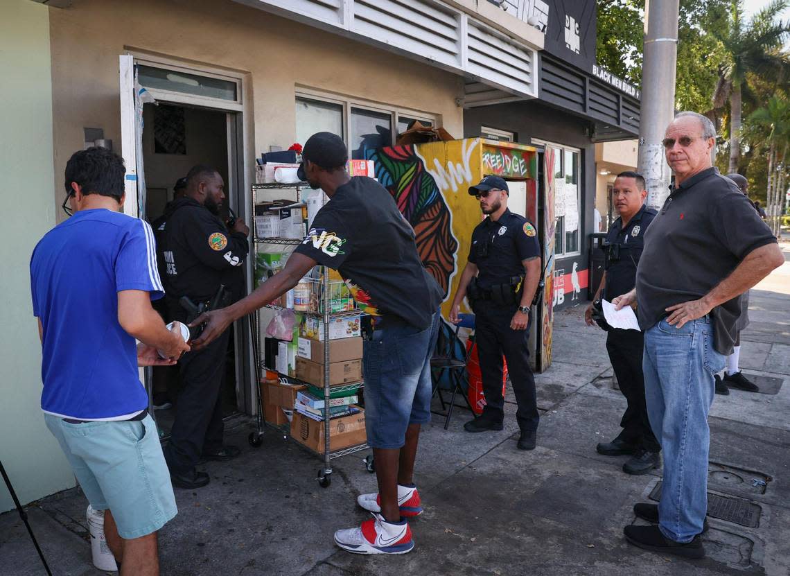 The Gator Investments landlord, right, watches people from the Village FREEdge food pantry try to get as much as they can out in under two hours while holding the eviction notice during an eviction of the food pantry on Monday, March 6, 2023, in Liberty City.