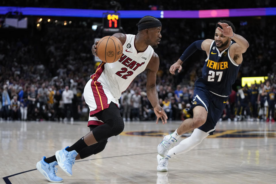 Miami Heat forward Jimmy Butler, left, moves the ball while defended by Denver Nuggets guard Jamal Murray, right, during the first half of Game 2 of basketball's NBA Finals, Sunday, June 4, 2023, in Denver. (AP Photo/Mark J. Terrill)