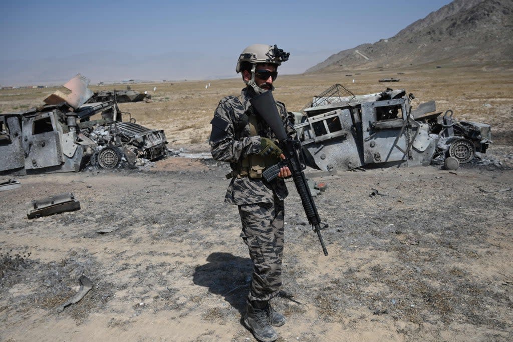 A member of the Taliban Badri 313 military unit stands besides damaged vehicles near Kabul (AFP via Getty Images)