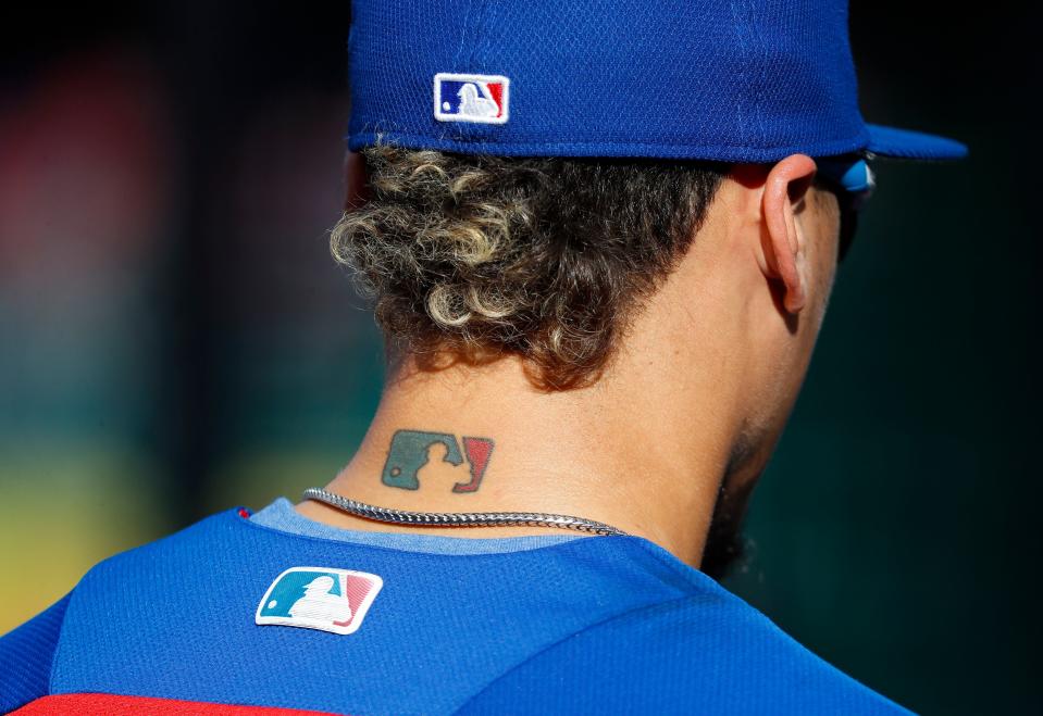 FILE - Then-Chicago Cubs' Javier Baez sports an MLB logo tattoo and logos on his hat and jersey as he waits to take batting practice before Game 2 of baseball's National League Division Series against the Washington Nationals at Nationals Park, Saturday, Oct. 7, 2017, in Washington. The clock ticked down toward the expiration of Major League Baseball's collective bargaining agreement at 11:59 p.m. EST Wednesday night, Dec. 1, 2021, and what was likely to be a management lockout ending the sport's labor peace at over 26 1/2 years. (AP Photo/Pablo Martinez Monsivais, File)