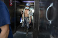 A construction worker wearing a face mask to protect against the coronavirus walks out of an elevator in Beijing, Wednesday, July 29, 2020. China reported more than 100 new cases of COVID-19 on Wednesday as the country continues to battle an outbreak in Xinjiang. (AP Photo/Mark Schiefelbein)